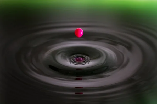緑の水に落ちるピンクのクリームのドロップの美しいイメージ — ストック写真