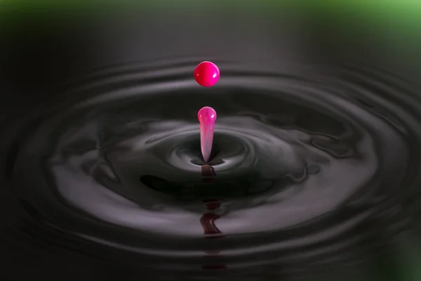 緑の水に落ちるピンクのクリームのドロップの美しいイメージ — ストック写真