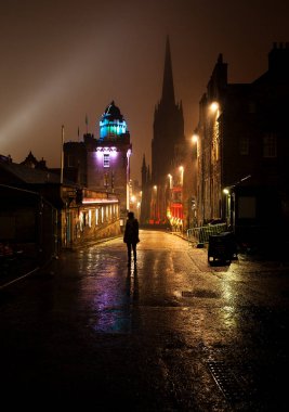 İskoçya 'nın Edinburgh şehrinde, yağmurlu bir kış gecesinde, bir kadının silueti ve ışıkların yansımasıyla... 