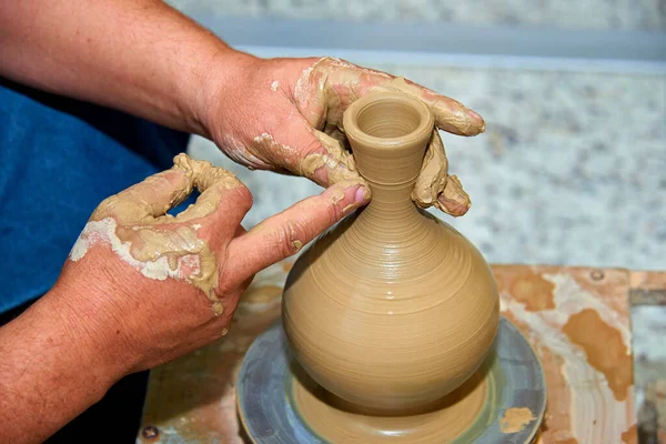 Hands of a potter. Potter making ceramic vase on the pottery wheel. Creating a vase of clay close-up.