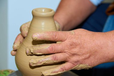 Çömlekçinin elleri. Potter çömlek çarkında seramik vazo yapıyor. Kil yakın plan bir vazo oluşturuluyor.  