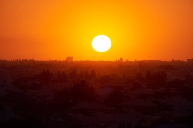 Şehrin üzerinde parlak turuncu gün doğumu