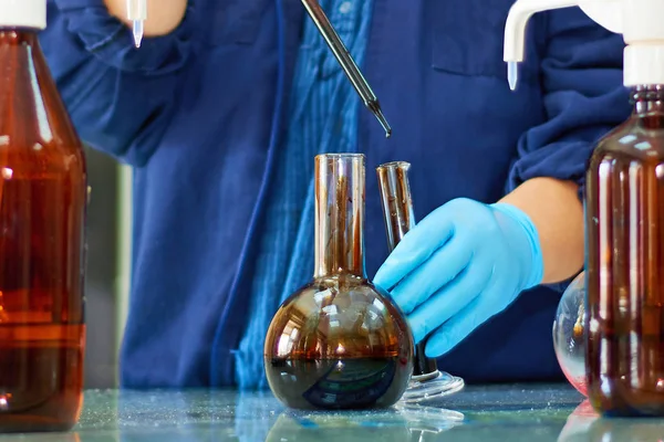 Ham petrollü laboratuvar şişesi. Arka planda laboratuvar test petrolü.
