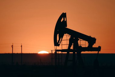 Gün batımında yağ pompası. Dünya Petrol Endüstrisi. Petrol pompası, bir petrol kuyusunda karşılıklı piston pompası için zemin üstü sürücüsüdür..