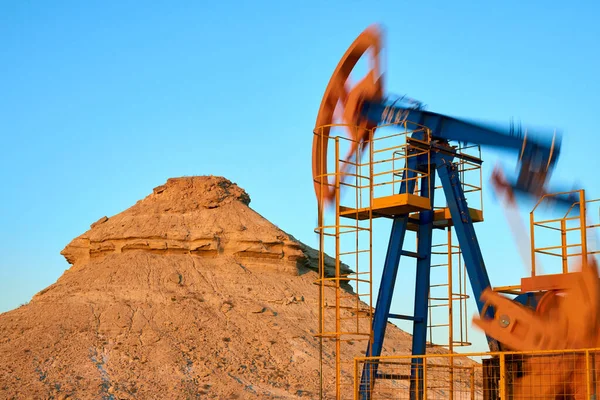 Mavi gökyüzü arka planında yağ pompası çalışıyor. Bulanık etki. Dünya Petrol Endüstrisi. Kazakistan 'ın batı bölgesi. Petrol pompası, petrol kuyusunda karşılıklı piston pompası için zemin motorudur..