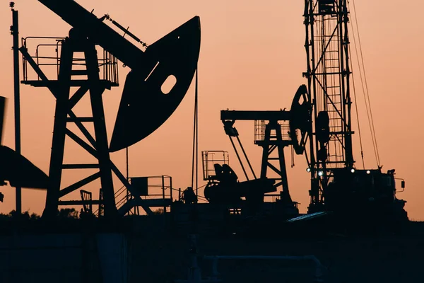 石油ポンプオイルリグ設計のための日没の背景に石油のエネルギー産業機械 ロイヤリティフリーのストック画像