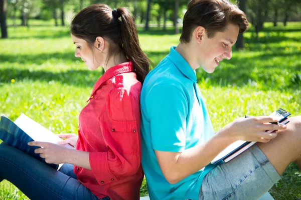 Two students studying in park on grass with outdoors