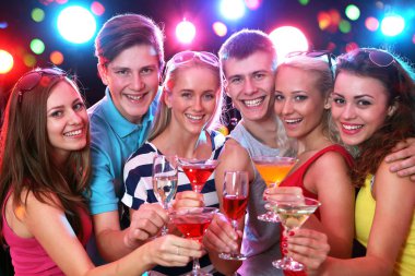 Mutlu bir grup genç arkadaş bardaklara dokunuyor.