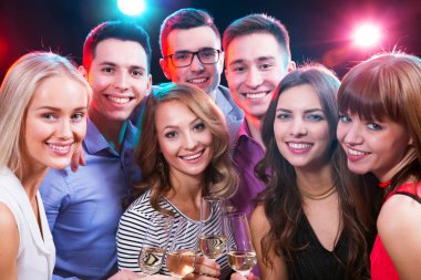 Mutlu bir grup genç arkadaş bardaklara dokunuyor.