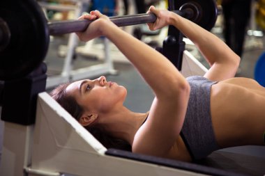  Spor salonunda halterle egzersiz yapan bir kadın..