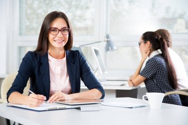 Ofiste gülümseyen genç ve çekici bir kadının portresi.