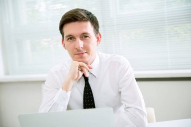 Dizüstü ofiste çalışan yakışıklı genç işadamı. 