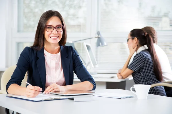 Ofiste gülümseyen genç ve çekici bir kadının portresi.