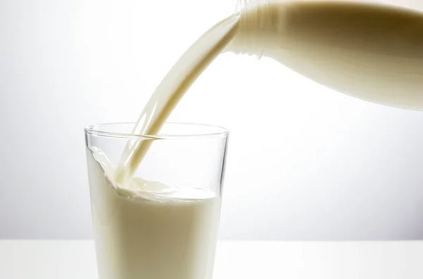 Pouring a glass of milk from bottle — Stock Photo, Image