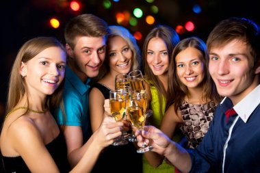 Mutlu bir grup genç arkadaş bardaklara dokunuyor.