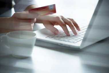 Kredi kartı tutan ve dizüstü bilgisayar kullanarak iş kadını.