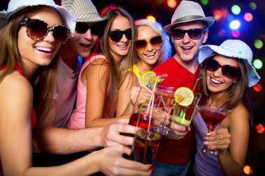 Mutlu bir grup genç arkadaş bardaklara dokunuyor.