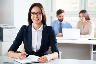 Ofiste gülümseyen genç ve çekici bir kadının portresi.