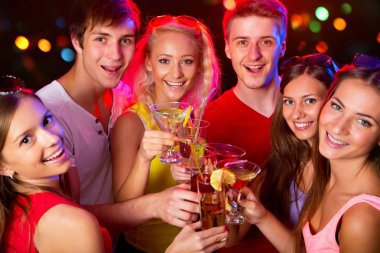 Mutlu bir grup genç arkadaş bardaklara dokunuyor.