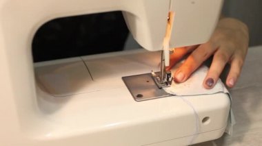 Kız dikiş makinesine tıbbi maske dikiyor, korona virüsü koruması. Bu süreçte ev yapımı tıbbi maske.