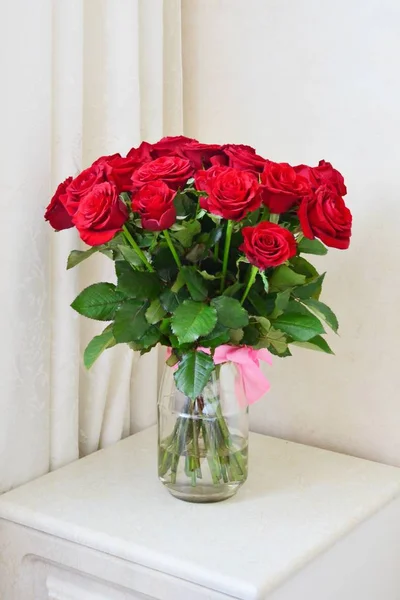 Bouquet di rose rosse in vaso di vetro su tavolo bianco — Foto Stock