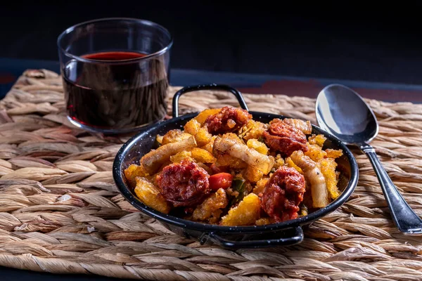 Migas de Extremadura, Extremadura 'dan tipik bir yemek, ekmek kırıntıları, pastırma, kırmızı ve yeşil biber, sarımsak ve kırmızı biber, bir bardak esparto masa örtüsü üzerine kırmızı şarap.