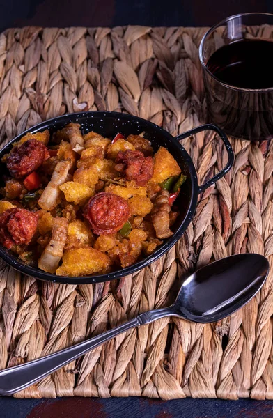 Migas de Extremadura, Extremadura 'dan tipik bir yemek, ekmek kırıntıları, pastırma, kırmızı ve yeşil biber, sarımsak ve kırmızı biber, bir bardak esparto masa örtüsü üzerine kırmızı şarap.