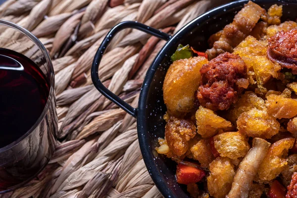 Extremadura kırıntıları, Extremadura 'dan tipik bir yemek, ekmek kırıntıları, pastırma, kırmızı ve yeşil biber, sarımsak ve kırmızı şarap, bir bardak esparto masa örtüsü üzerine kırmızı şarap.