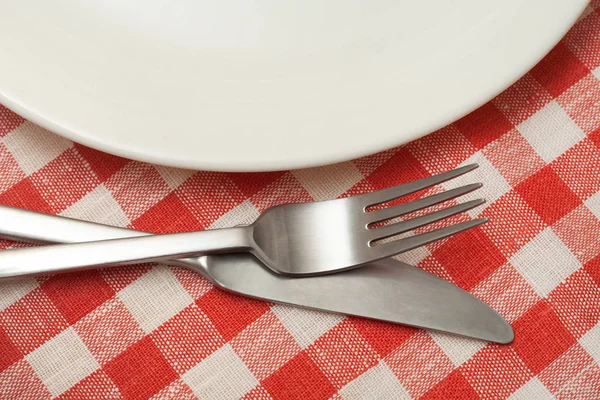 市松模様のテーブル クロスの上の食器を有する空板. — ストック写真