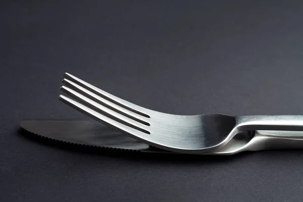 Gabel und Messer in Nahaufnahme auf schwarzem Hintergrund — Stockfoto