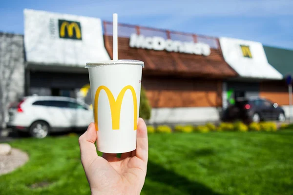 Минск, Беларусь, 18 мая 2017 года: Бумажный стаканчик для безалкогольных напитков McDonald 's на фоне размытого ресторана McDonald' s — стоковое фото