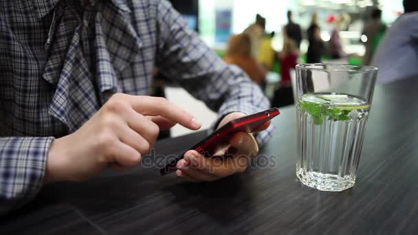 女人使用电话，在咖啡馆里喝水 — 图库视频影像