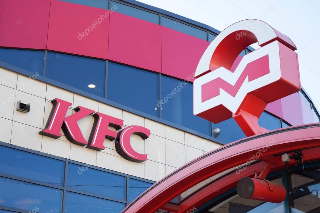 KFC fast food restaurant next to entrance to subway. Logos of KFS and Metro of Minsk