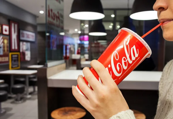 30 октября 2017 г.: Кока-кола безалкогольный напиток. Женщина пьет кока-колу в кафе . — стоковое фото