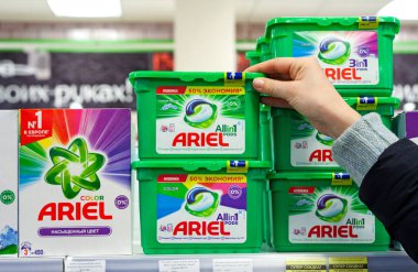 MINSK, BELARUS - February 2, 2020: A buyer takes Ariel washing powder from a supermarket shelf. Woman purchases washing powder at supermarket clipart