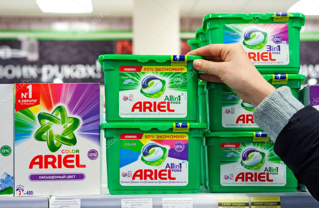 MINSK, BELARUS - February 2, 2020: A buyer takes Ariel washing powder from a supermarket shelf. Woman purchases washing powder at supermarket