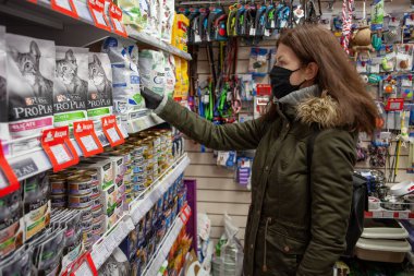 MINSK, BELARUS - 27 Nisan 2020: koruyucu maske giyen alıcı. Salgın sırasında alışveriş yapmak. Evcil hayvan dükkanında alışveriş yapan adam..