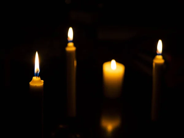 Öndeki muma odaklanmış farklı boyutlarda mumlar yakıyor.