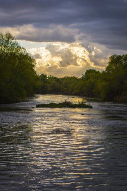 Arka planda fırtınalı bulutlar olan çok hızlı akan bir nehrin görüntüsü