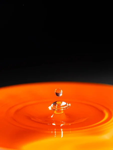 Şekilleri ve siyah arkaplanı olan turuncu su damlasının soyut görüntüsü