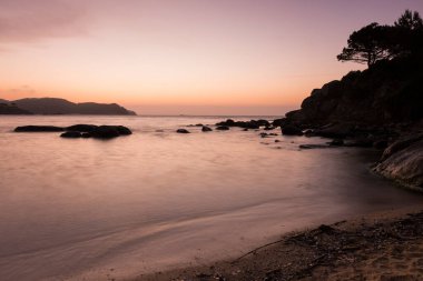 Sahilde kayalar ve ufukta bir ada var.