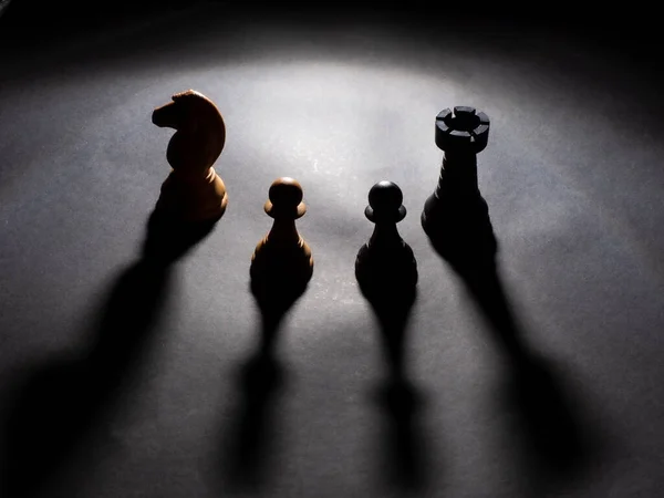 Beyaz şövalye, siyah kale, siyah piyon ve siyah arka planı olan beyaz piyon.