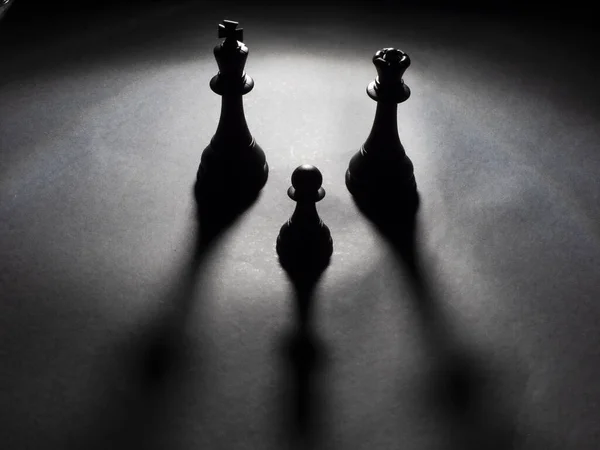 Siyah kral ve kraliçe satranç resmi ve siyah arka planda siyah bir piyon.