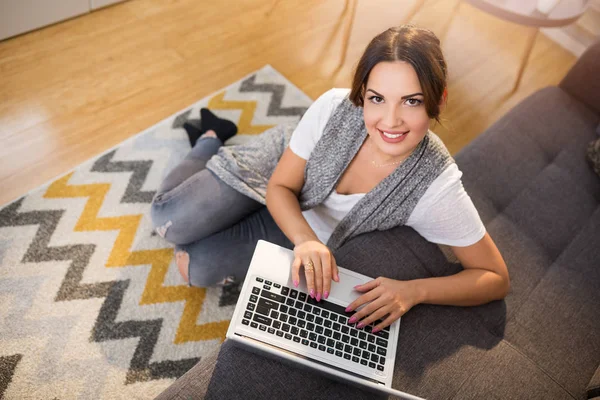Femme assise sur un tapis tapant sur un ordinateur portable — Photo