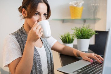 Dizüstü bilgisayar kullanarak ve çay içme kadın