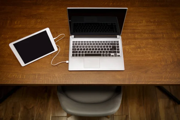 Tablet connected with laptop on desk — Stock Photo, Image