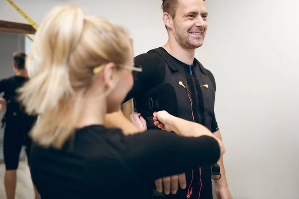 Hombre feliz en traje de ems y mujer ayudándole a ponérselo — Foto de Stock