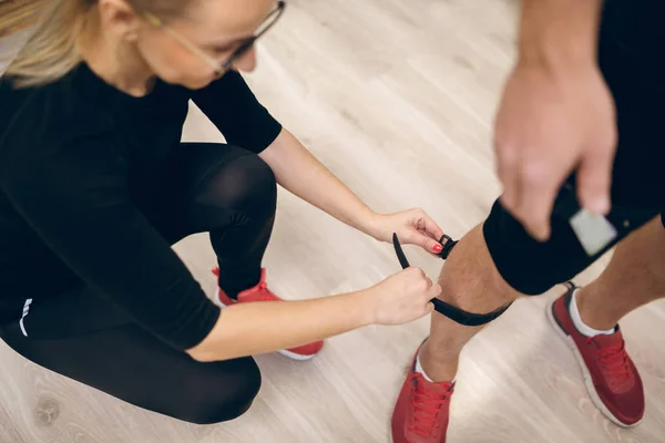 Cinturón de sujeción de entrenador femenino en pierna de hombre — Foto de Stock