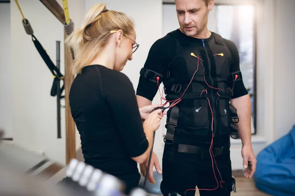 Entraîneur femelle connectant les câbles sur sportsman ems costume — Photo