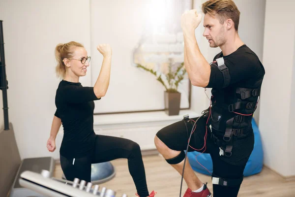 Joven deportista haciendo ems entrenamiento con entrenador personal — Foto de Stock